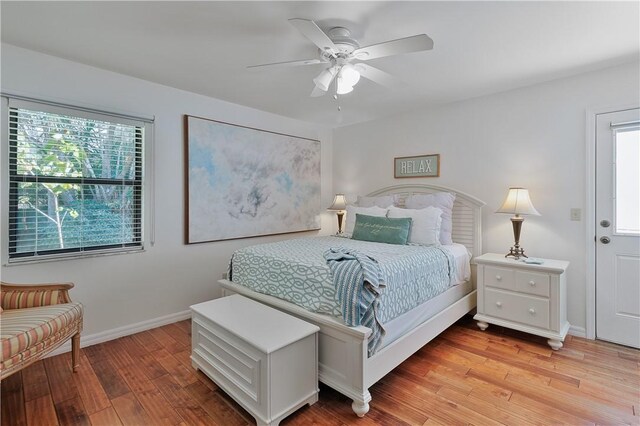 bedroom featuring ceiling fan, light hardwood / wood-style floors, and multiple windows