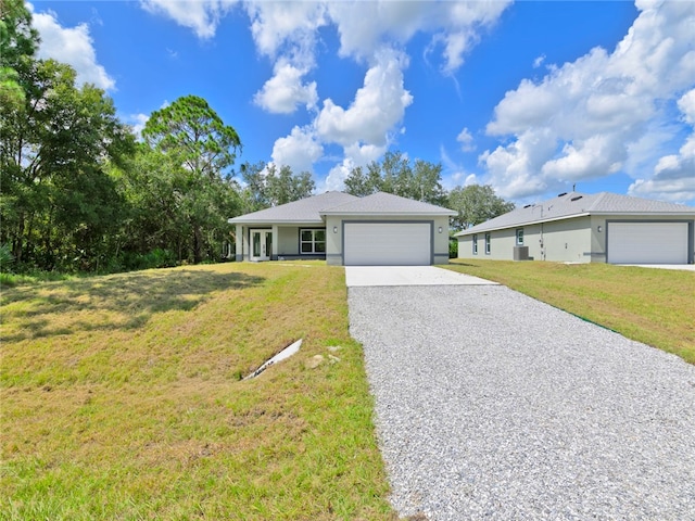 ranch-style home featuring cooling unit, a garage, and a front yard