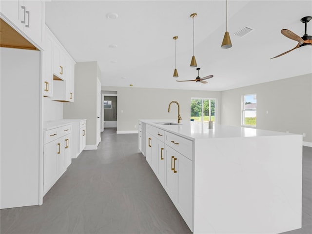 kitchen featuring white cabinets, pendant lighting, a kitchen island with sink, and sink