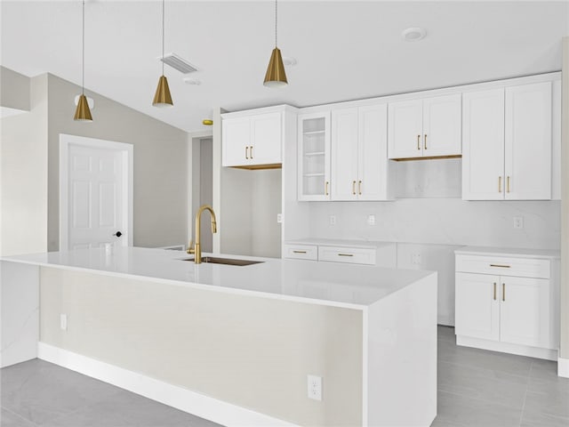 kitchen featuring pendant lighting, white cabinets, sink, and a kitchen island with sink