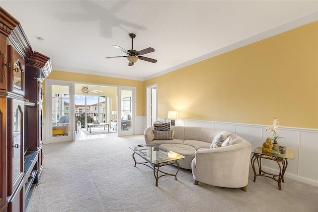 living room with ceiling fan, ornamental molding, and light carpet