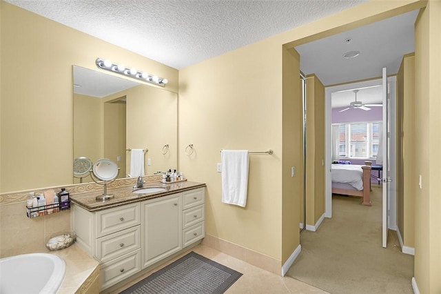 bathroom featuring a textured ceiling, vanity, a tub, ceiling fan, and tile patterned flooring