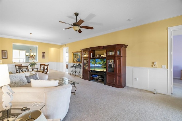 carpeted living room with crown molding and ceiling fan with notable chandelier