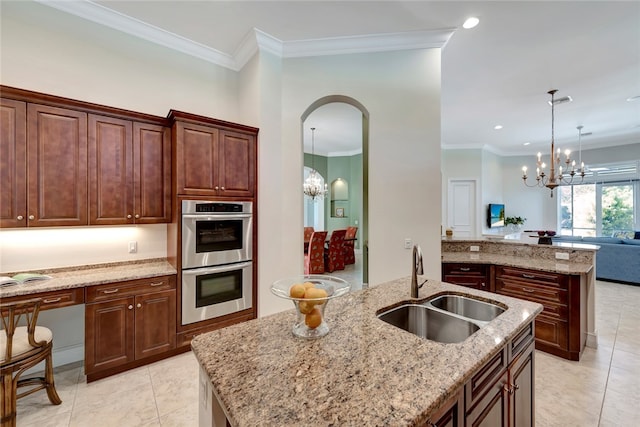 kitchen featuring an island with sink, a chandelier, sink, and double oven