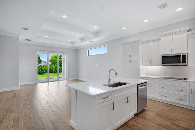 kitchen with white cabinets, a center island with sink, sink, and appliances with stainless steel finishes