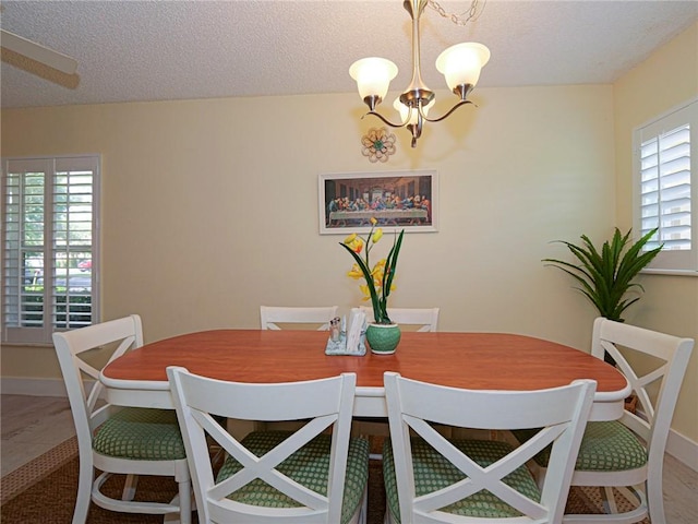 14 Vista Gardens Trl Unit 102, Vero Beach, FL 32962 - dining room featuring a chandelier, a textured ceiling, and baseboards