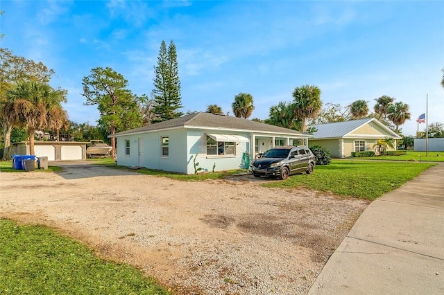 ranch-style home featuring a garage, a front yard, and an outbuilding