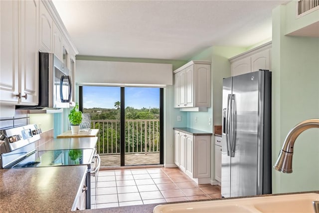 kitchen with light tile patterned floors, visible vents, white cabinets, appliances with stainless steel finishes, and dark countertops