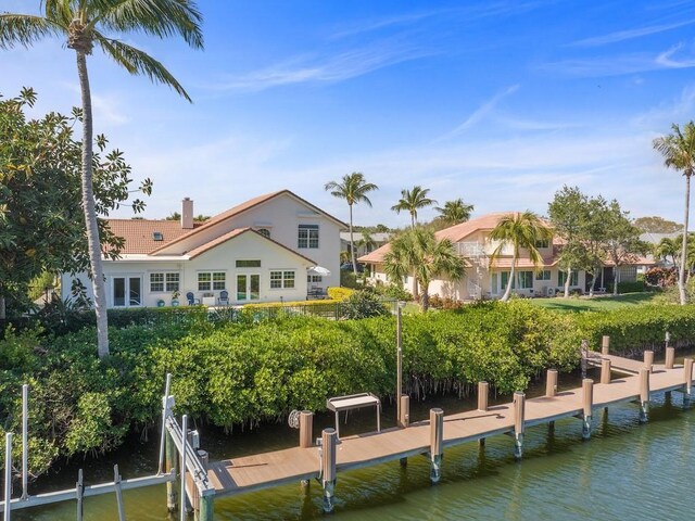 1880 Cobia Dr, Vero Beach, FL 32960 - rear view of house with a tile roof, a water view, a chimney, and stucco siding