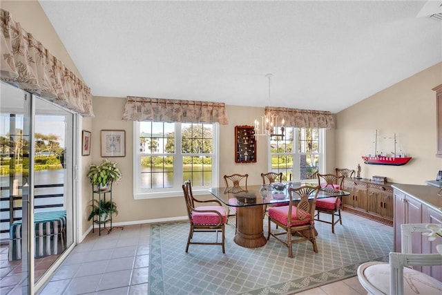 tiled dining area with a chandelier, plenty of natural light, and lofted ceiling