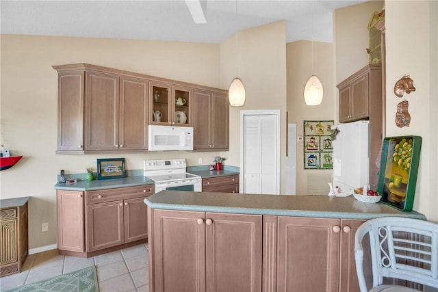 kitchen featuring decorative light fixtures, light tile patterned flooring, white appliances, and kitchen peninsula