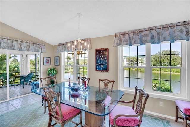 tiled dining room featuring a chandelier, a water view, vaulted ceiling, and plenty of natural light