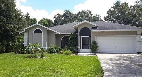 ranch-style house featuring a garage and a front lawn