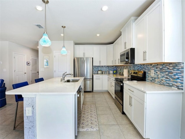 kitchen with appliances with stainless steel finishes, hanging light fixtures, white cabinets, and a breakfast bar area