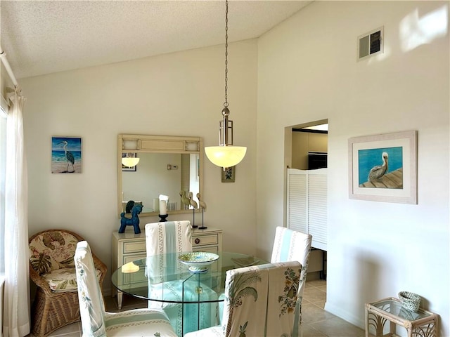 dining area with vaulted ceiling, light tile patterned flooring, and a textured ceiling