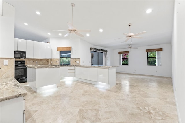 kitchen with a kitchen island, white cabinets, light stone counters, and black appliances