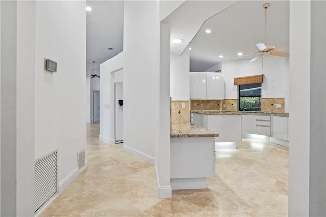 kitchen featuring white cabinetry, tasteful backsplash, kitchen peninsula, ceiling fan, and white refrigerator with ice dispenser