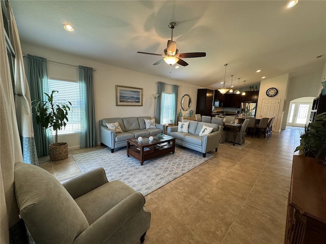 living room with ceiling fan, light tile patterned floors, and lofted ceiling