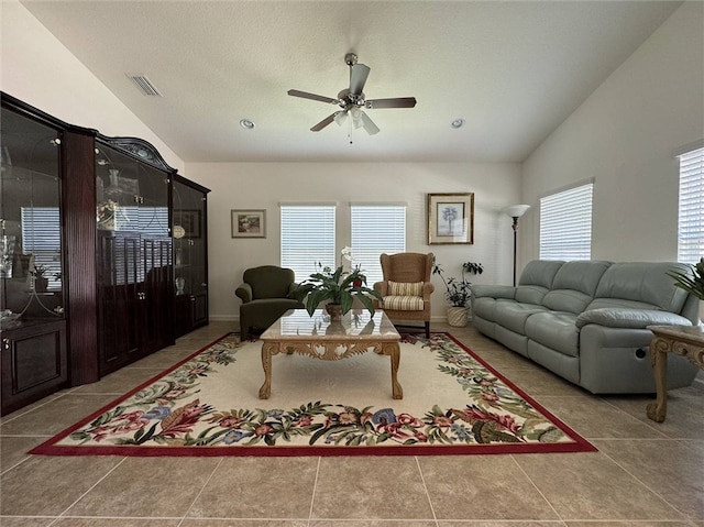 tiled living room with a textured ceiling, a healthy amount of sunlight, ceiling fan, and vaulted ceiling