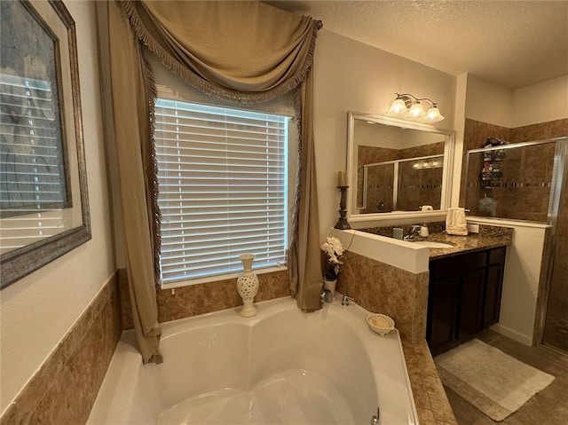 bathroom with vanity, a textured ceiling, and plus walk in shower