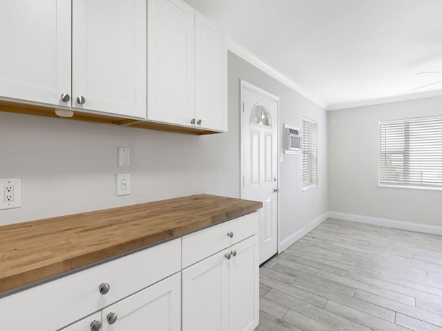 kitchen with butcher block countertops, white cabinetry, and ornamental molding