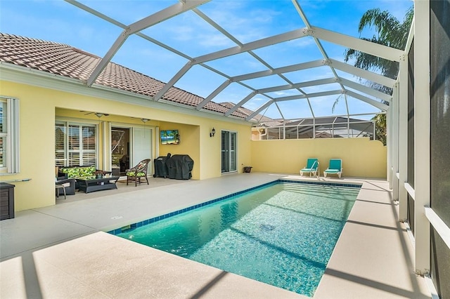 outdoor pool with glass enclosure, a patio, and ceiling fan