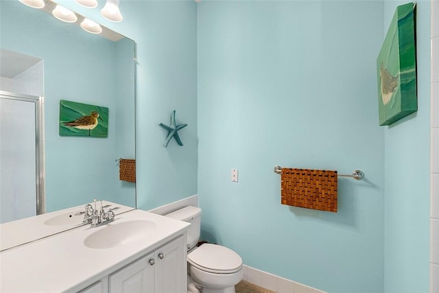 full bathroom with vanity, a shower with door, toilet, and baseboards