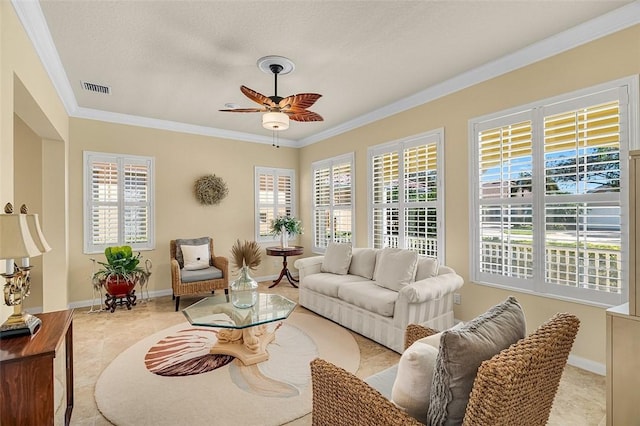 living area with baseboards, visible vents, a ceiling fan, and ornamental molding