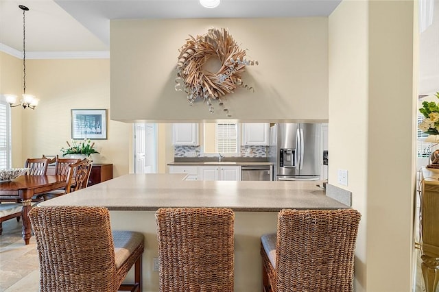 kitchen featuring a peninsula, a kitchen bar, appliances with stainless steel finishes, and decorative backsplash