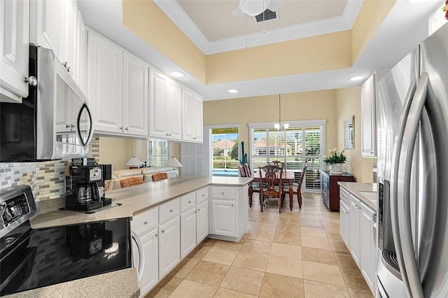 kitchen with stainless steel appliances, a peninsula, white cabinets, backsplash, and crown molding