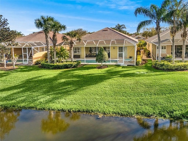 back of house featuring glass enclosure, a yard, a water view, and an outdoor pool