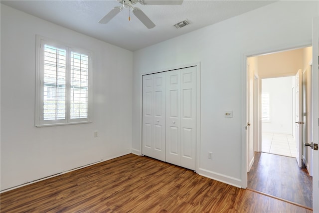 unfurnished bedroom featuring a textured ceiling, ceiling fan, a closet, and dark hardwood / wood-style floors