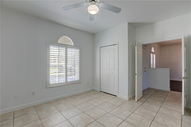 unfurnished bedroom featuring light tile patterned floors, a closet, multiple windows, and ceiling fan