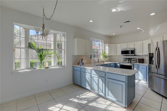 kitchen with hanging light fixtures, decorative backsplash, a notable chandelier, white cabinetry, and stainless steel appliances