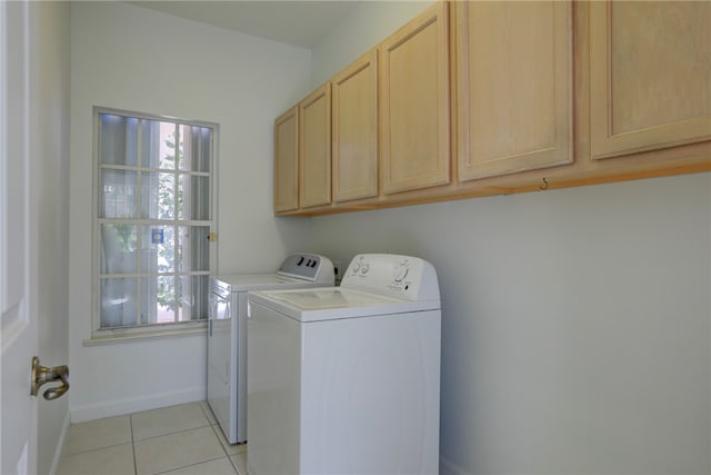 laundry room with cabinets, light tile patterned flooring, and washer and dryer