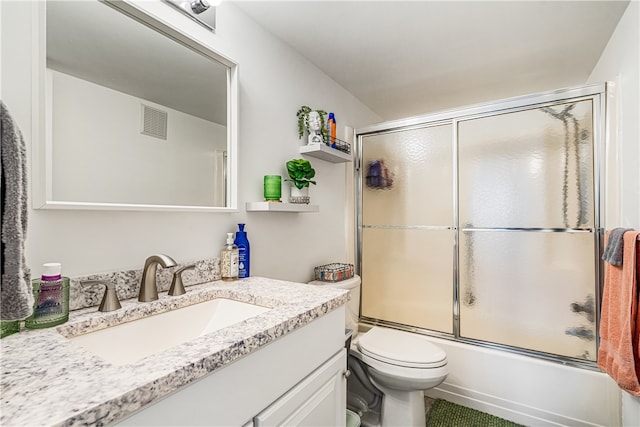 full bathroom featuring vanity, toilet, and shower / bath combination with glass door