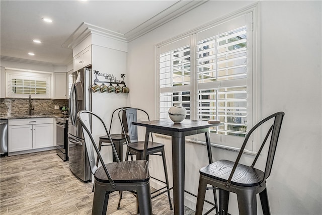 dining space featuring crown molding, sink, and light hardwood / wood-style flooring