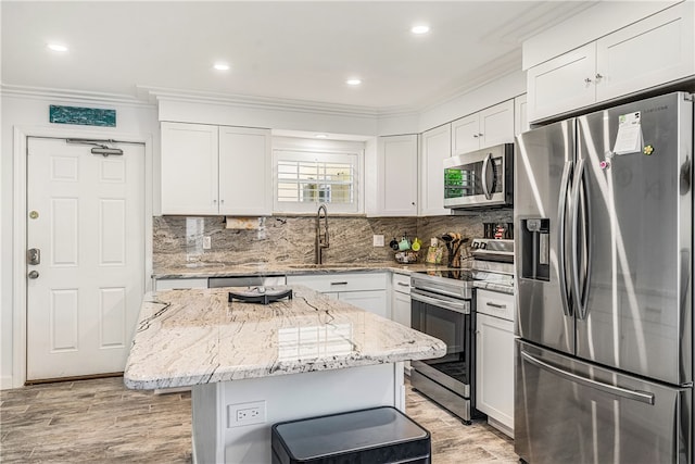 kitchen with white cabinets, a center island, stainless steel appliances, and light stone countertops