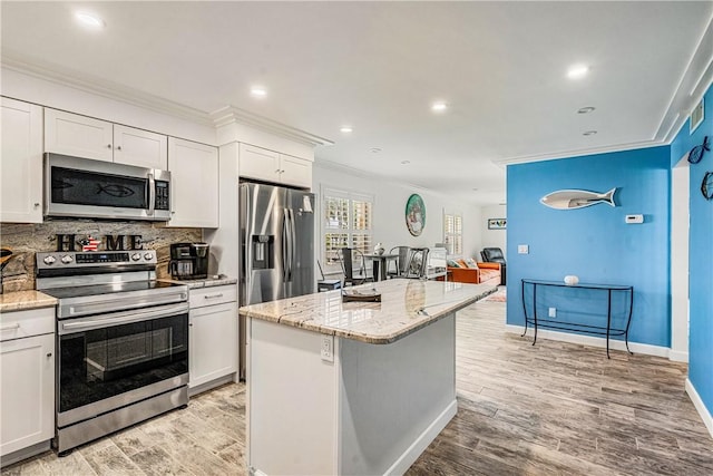 1441 Ocean Dr Unit 207, Vero Beach, FL 32963 - kitchen featuring stainless steel appliances, ornamental molding, light wood finished floors, white cabinetry, and decorative backsplash