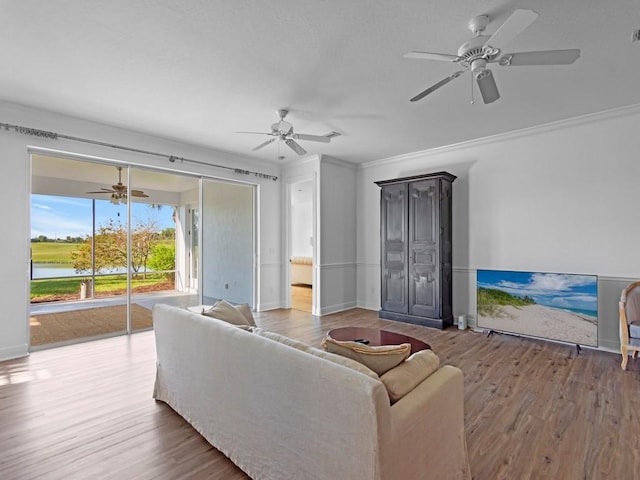 living area featuring ceiling fan, crown molding, baseboards, and wood finished floors