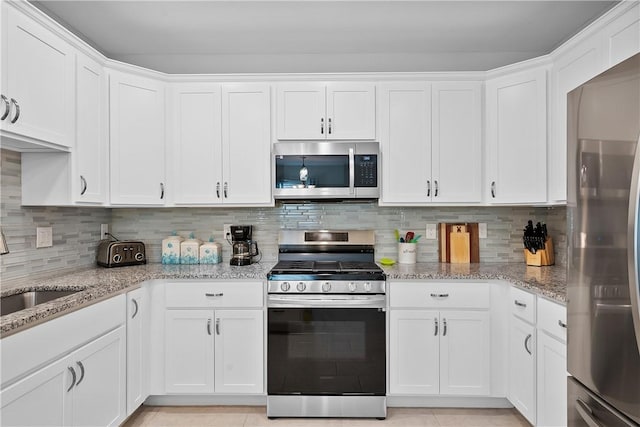 kitchen with backsplash, stainless steel appliances, and white cabinetry