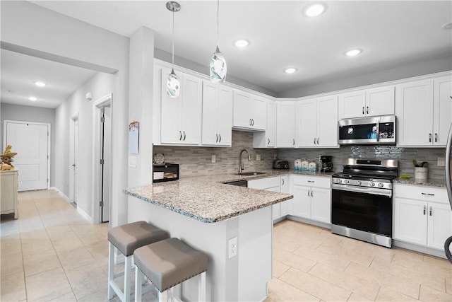 kitchen with a breakfast bar, appliances with stainless steel finishes, white cabinetry, and hanging light fixtures