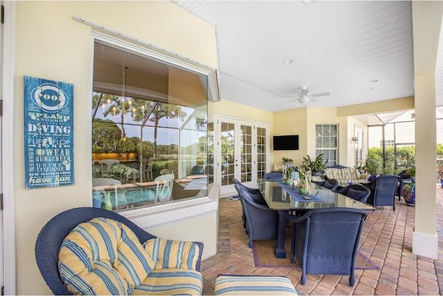 sunroom / solarium featuring ceiling fan with notable chandelier and french doors