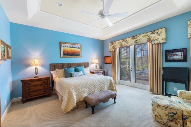 carpeted bedroom featuring a raised ceiling, ceiling fan, and access to outside