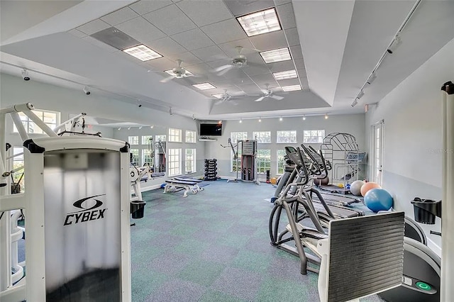 exercise room featuring a raised ceiling, ceiling fan, and a drop ceiling