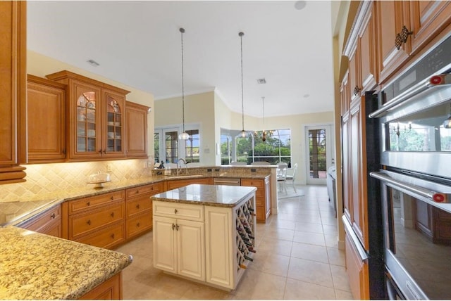 kitchen featuring decorative backsplash, appliances with stainless steel finishes, kitchen peninsula, decorative light fixtures, and a center island