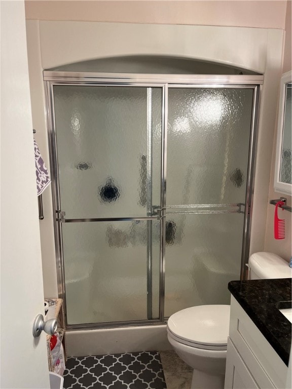 bathroom with walk in shower, vanity, tile patterned floors, and toilet