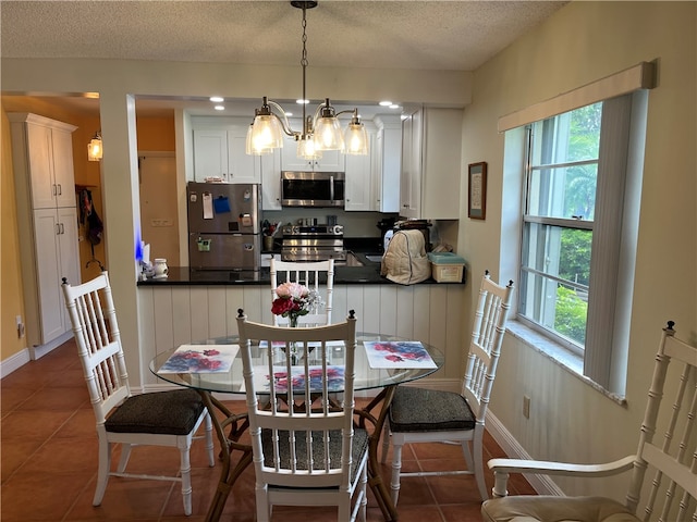 tiled dining area with a chandelier and a textured ceiling