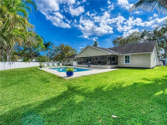 rear view of property featuring a fenced in pool, a yard, a patio area, and a sunroom