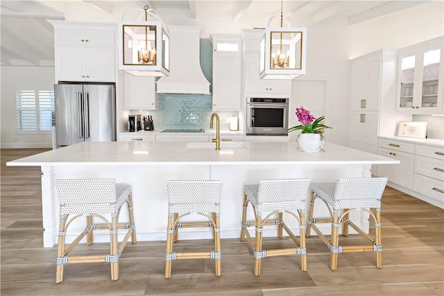 kitchen featuring sink, stainless steel appliances, a center island with sink, and hanging light fixtures